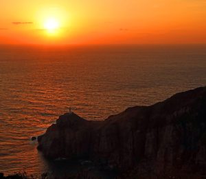 夕日に染まる海原と大瀬崎断崖。断崖の先端に大瀬埼灯台が立つ＝五島市玉之浦町